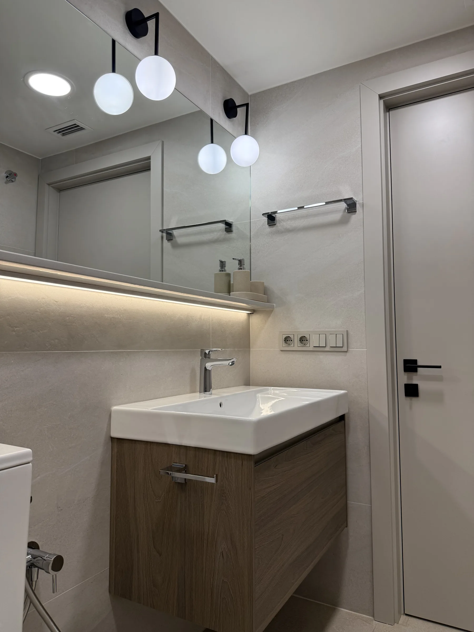 Baño de invitados con espejo iluminado y puerta gris