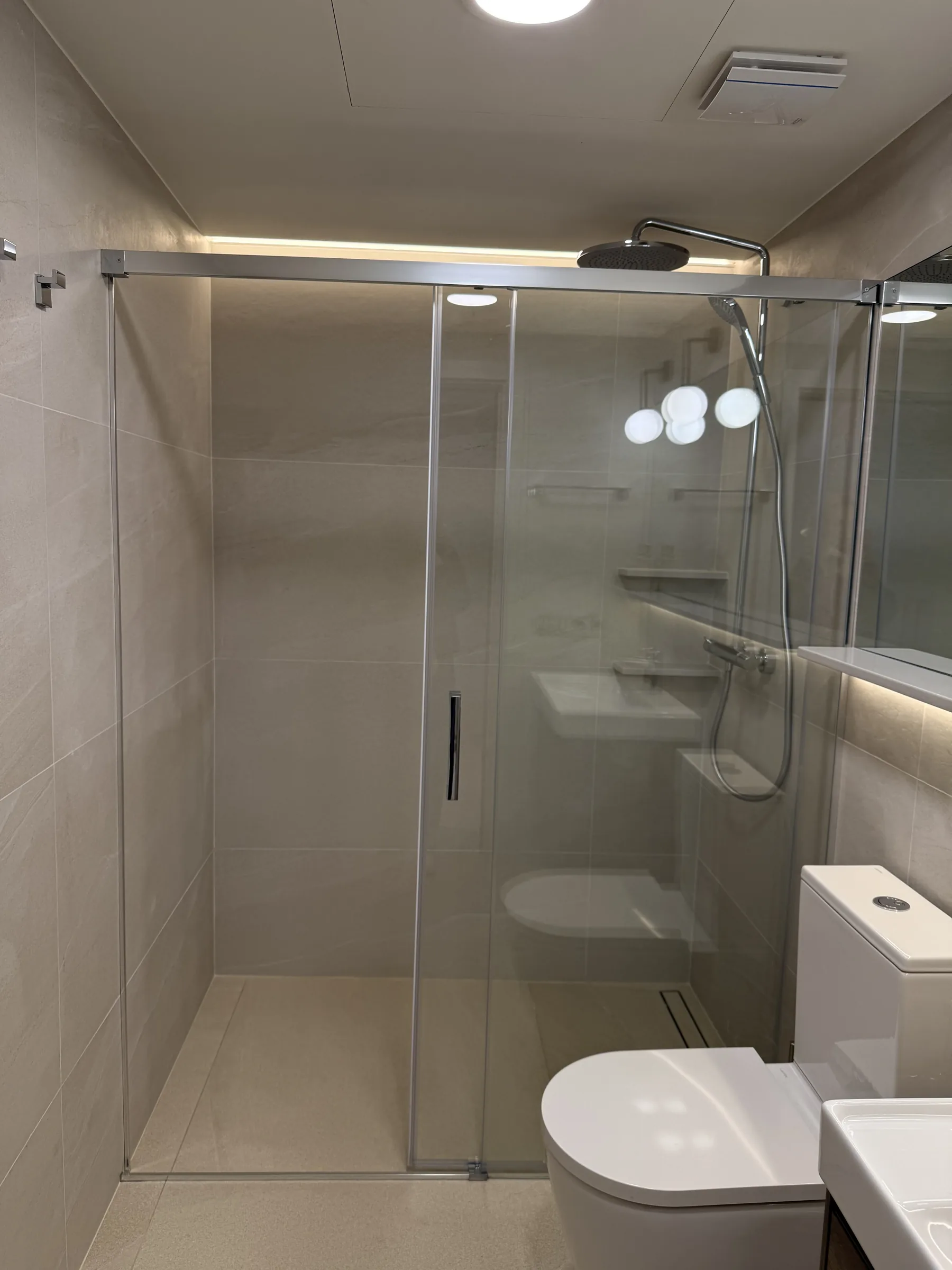 Ducha a ras de suelo con mampara corredera y hornacinas